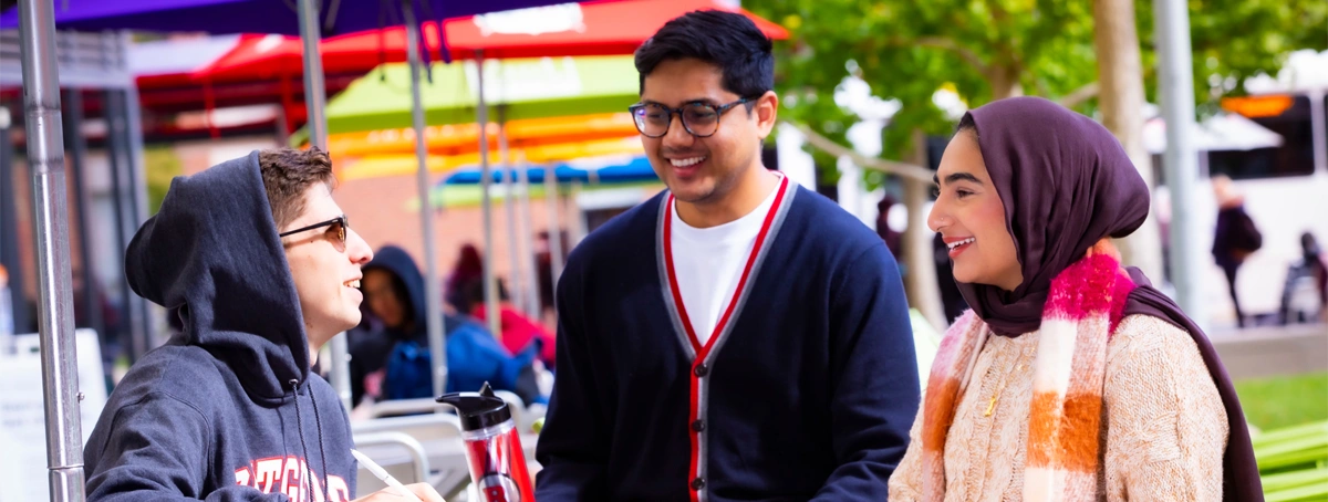 Eric Soares (SAS '26), Tahidul Ridoy (SGS), and Maryam Khalid (SAS '23) talk and enjoy a fall day outside at the Yard